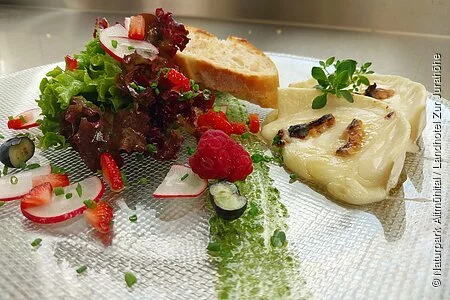 Ein Teller mit Ziegenkäse, Gemüse und ein paar scheiben Brot wird serviert